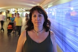 Abuse survivor, Kellie Roche, standing in a pedestrian tunnel in Sydney, with people walking behind her