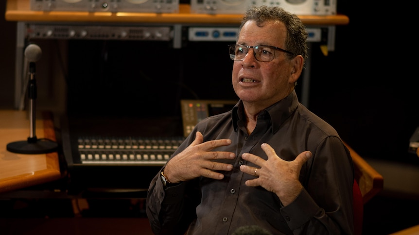 Lucky Oceans gestures with two hands on his chest while sitting in a music studio.