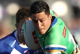 A Canberra Raiders NRL player carries the ball as he is tackled by a Canterbury opponent.