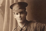 A historical photo portrait of a man in an army uniform from the World War I era, smiling at the camera.