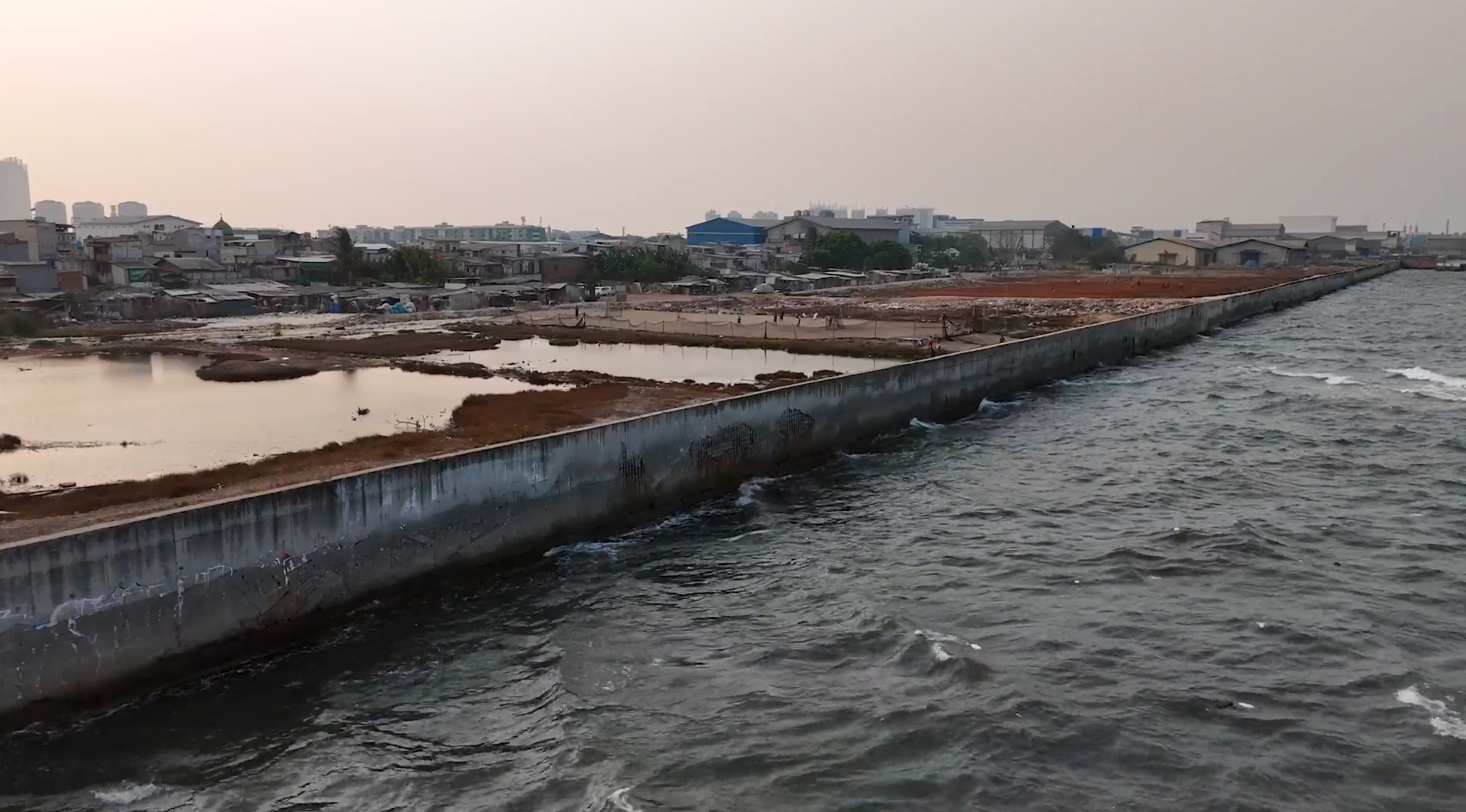 Long concrete seawalls like this are designed to protect Jakarta from ...