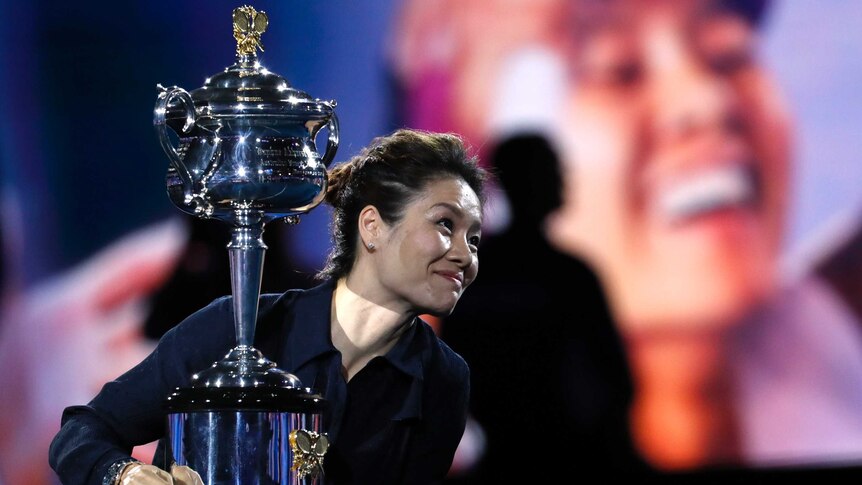 You view Li Na with a very shallow depth of field with her hands surrounding a large silver trophy.