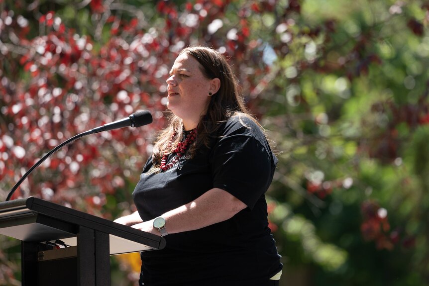 a woman speaking outdoors at a podium