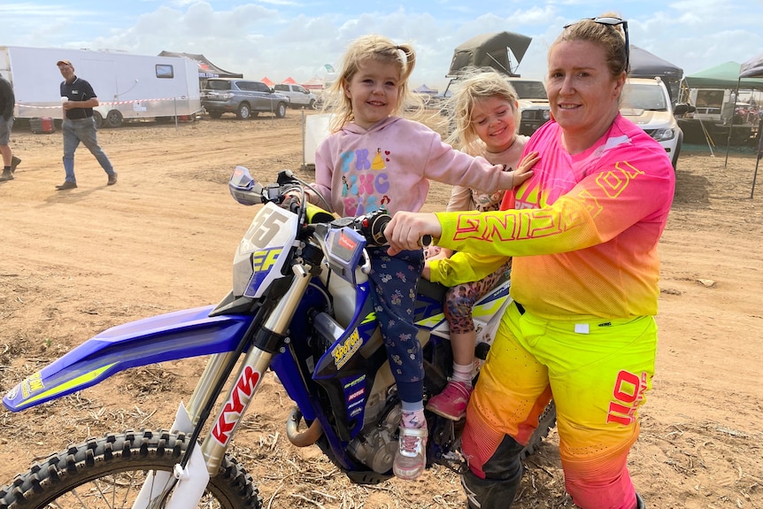 A woman and two little girls with a motorbike.
