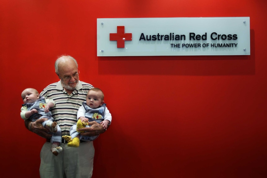 James Harrison at the Red Cross holding two babies.