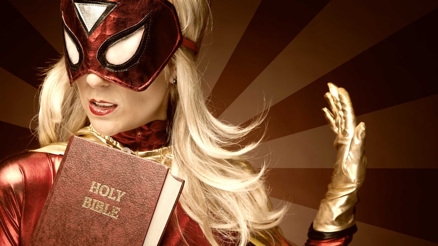 Blonde woman wearing superhero mask and costume, and carrying the Bible.