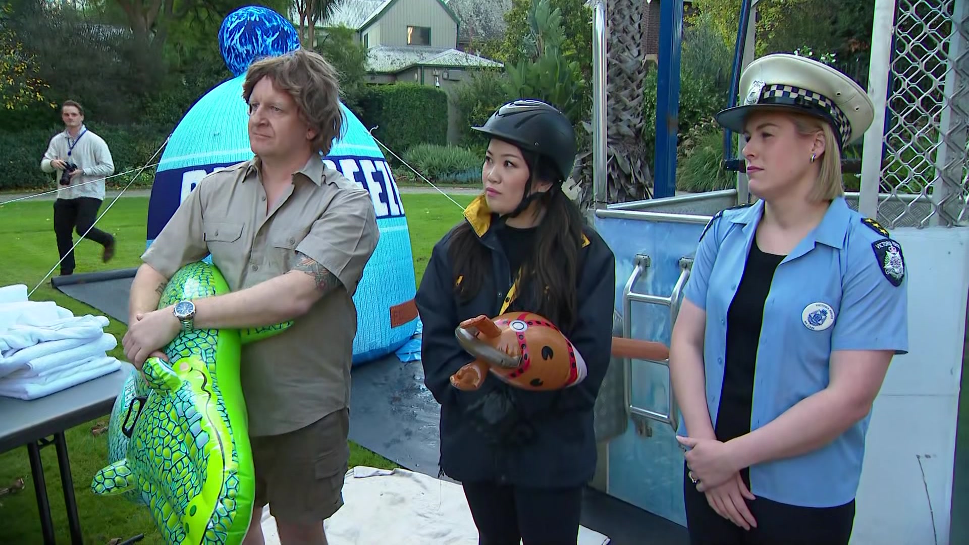 A man dressed as Steve Irwin with a blow-up crocodile a woman with a hobby horse and helmet and a woman dressed as a cop.