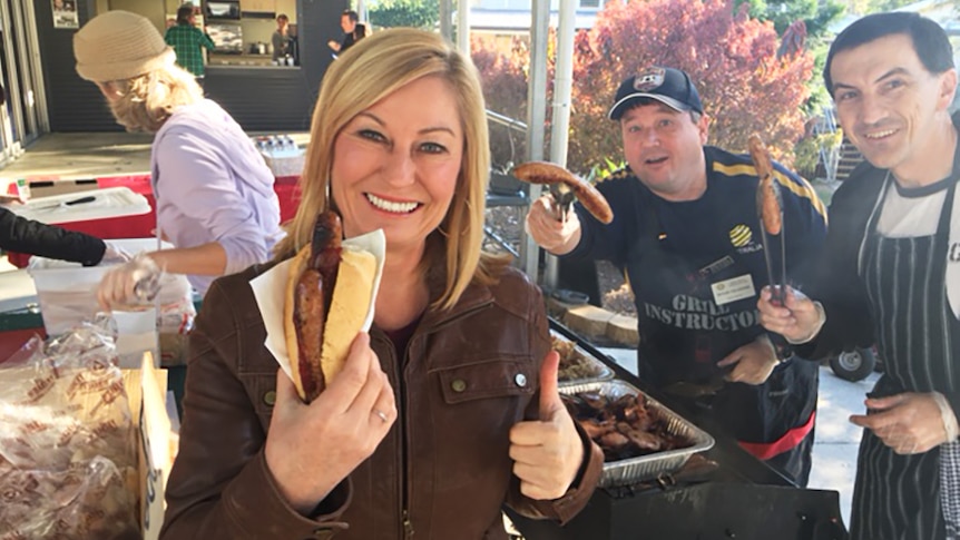 ABC reporter Lexy Hamilton-Smith holding a two-sausage bun at an election barbecue in Brisbane