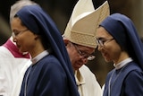 Nuns walk past Pope Francis during a mass.