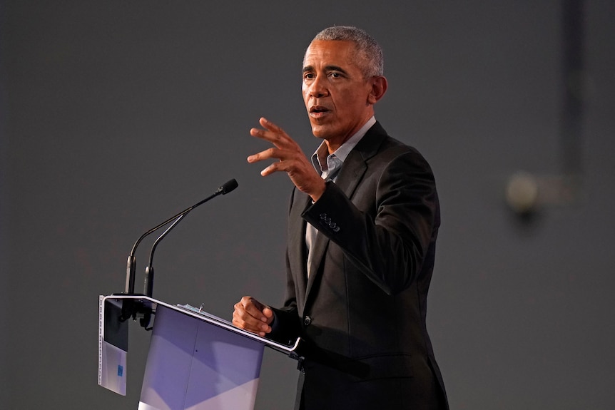 A man speaks in front of a podium 