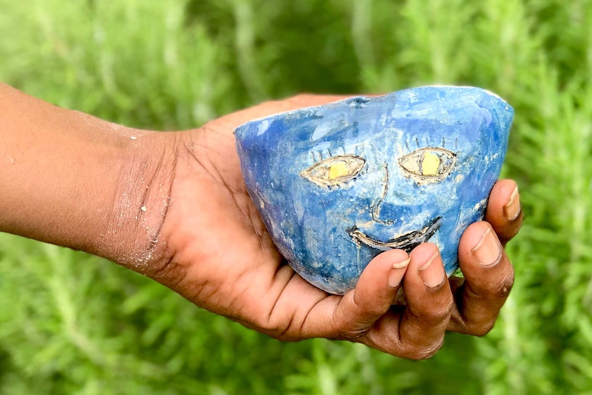 A hand holding a pot.