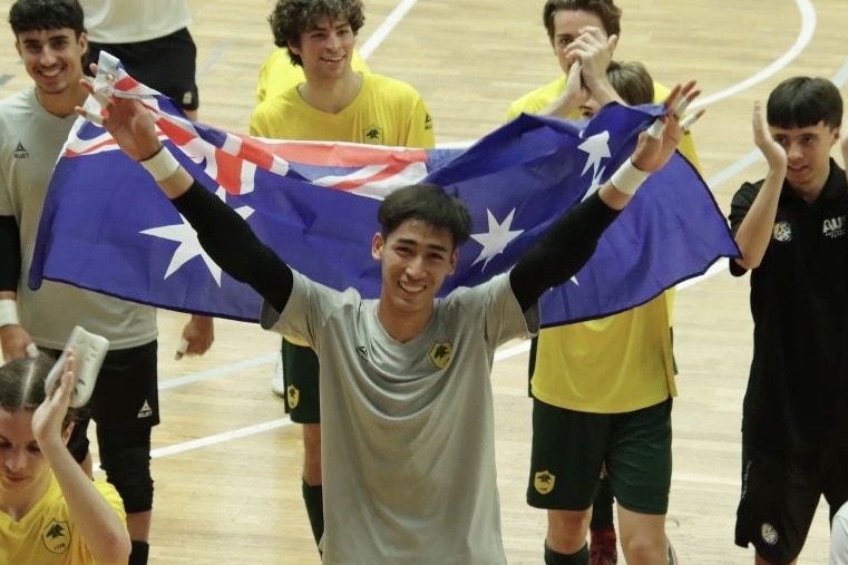 A young man holds up the Australian flag