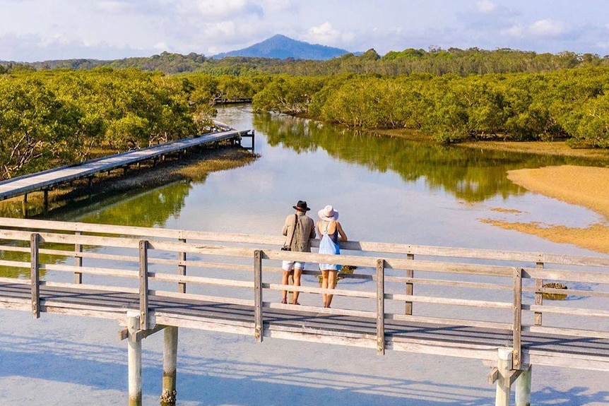 a man and a woman standing on a boardwalk overlooking a river