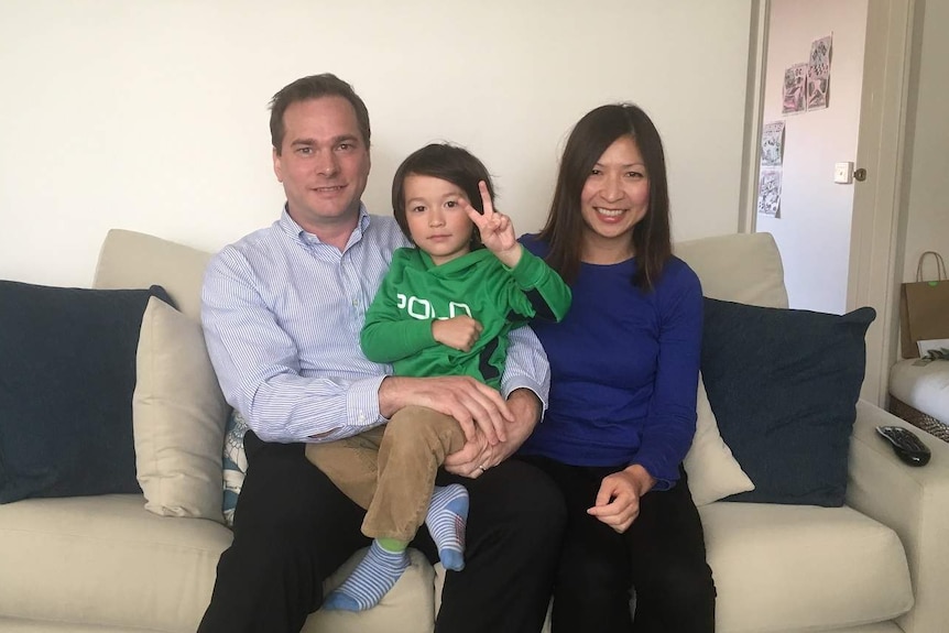 Chris and Hong Daley and their son, Marcus, sit on the couch in their living room.