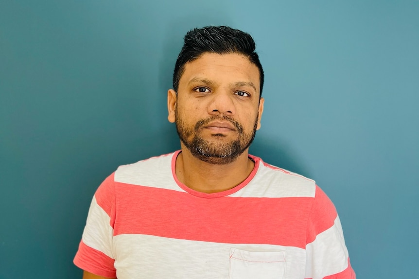 Shaid Islam's friend Maxi Haque looking at camera with blue background