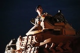 A Turkish army officer sits atop this tank at night.