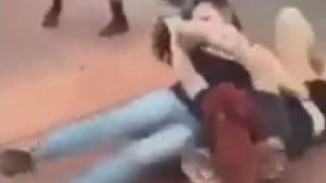 Two girls fighting on the ground.