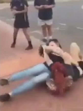 Two girls fighting on the ground.