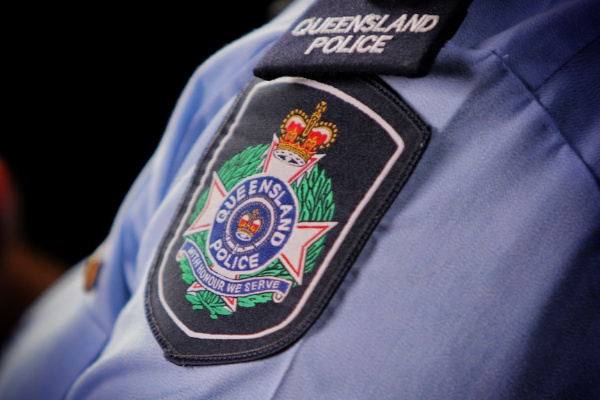 Queensland Police Service logo on shoulder sleeve of officer's shirt.