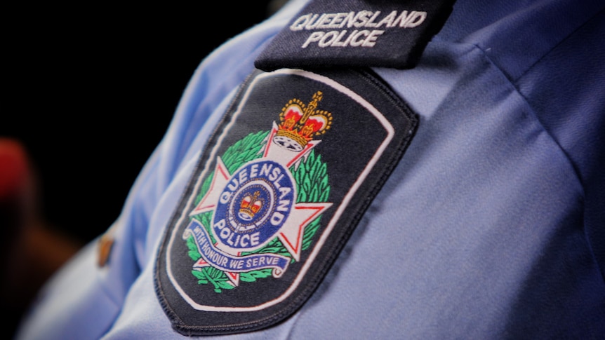 Queensland Police Service logo on shoulder sleeve of officer's shirt.