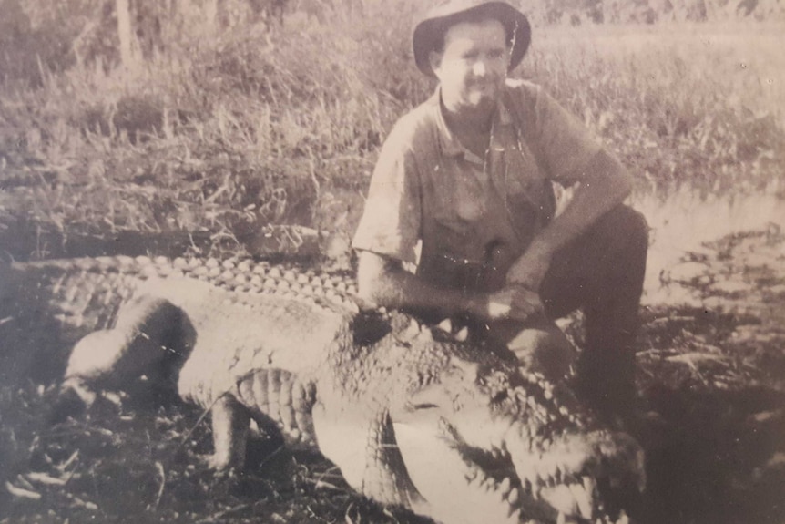 A black and white photo of a man with a dead crocodile