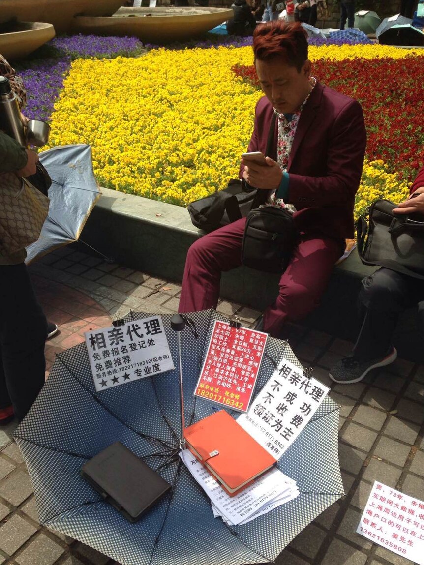 A dating agent sits at a park in Shanghai, looking for business.
