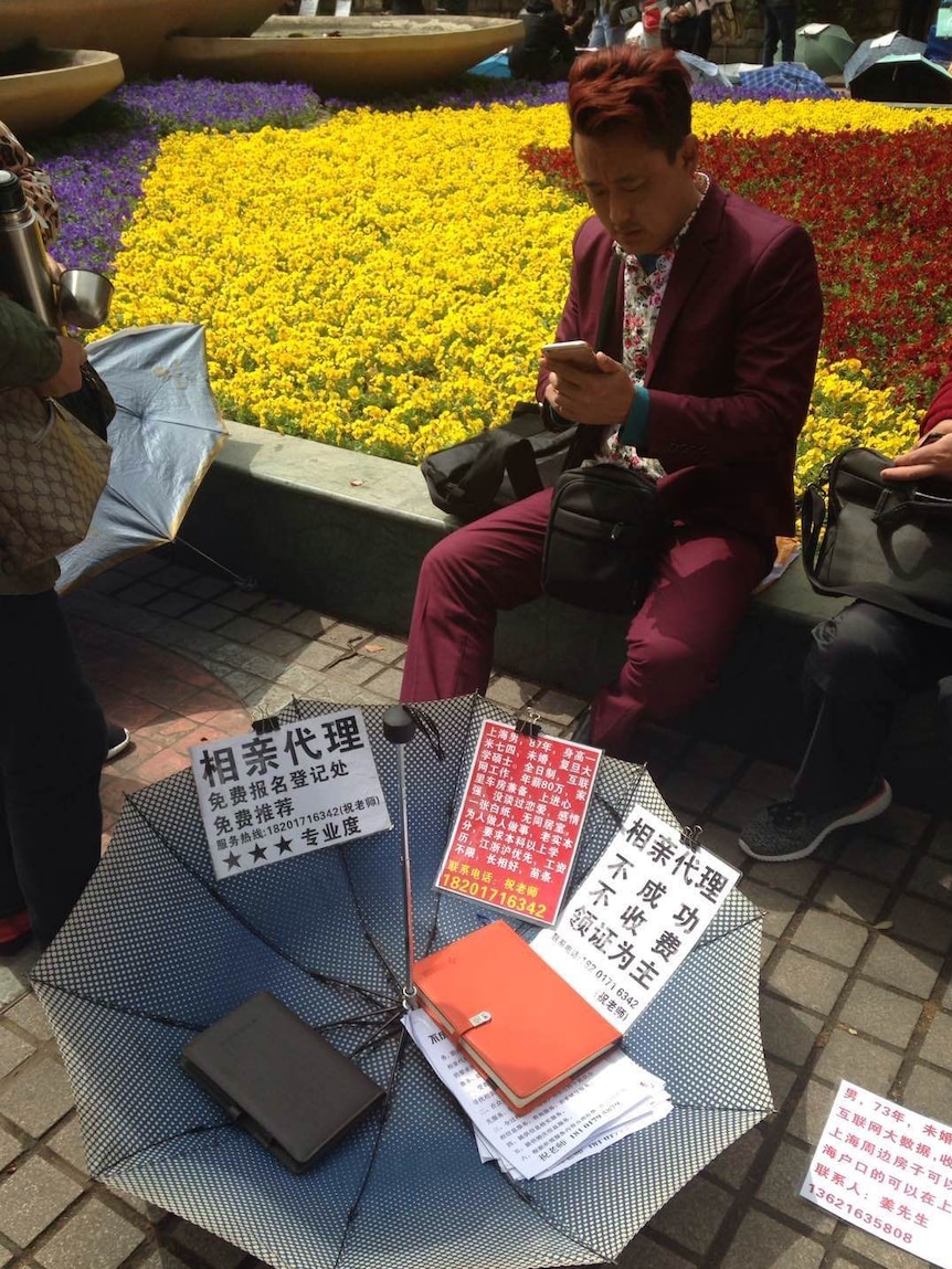 A dating agent sits at a park in Shanghai, looking for business.