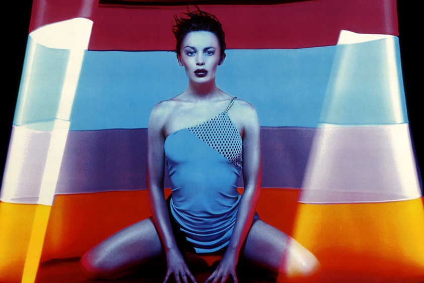 The cover of Kylie Minogue's Impossible Princess album, featuring Kylie kneeling in front of a colourful background.