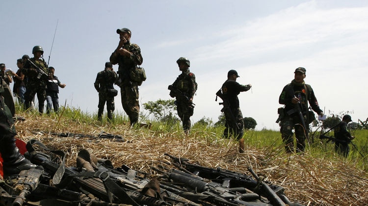 Soldiers stand guard near assorted firearms unearthed in southern Philippines.