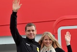 Cadel Evans and wife Chiara wave from the steps of the Qantas plane they arrived on