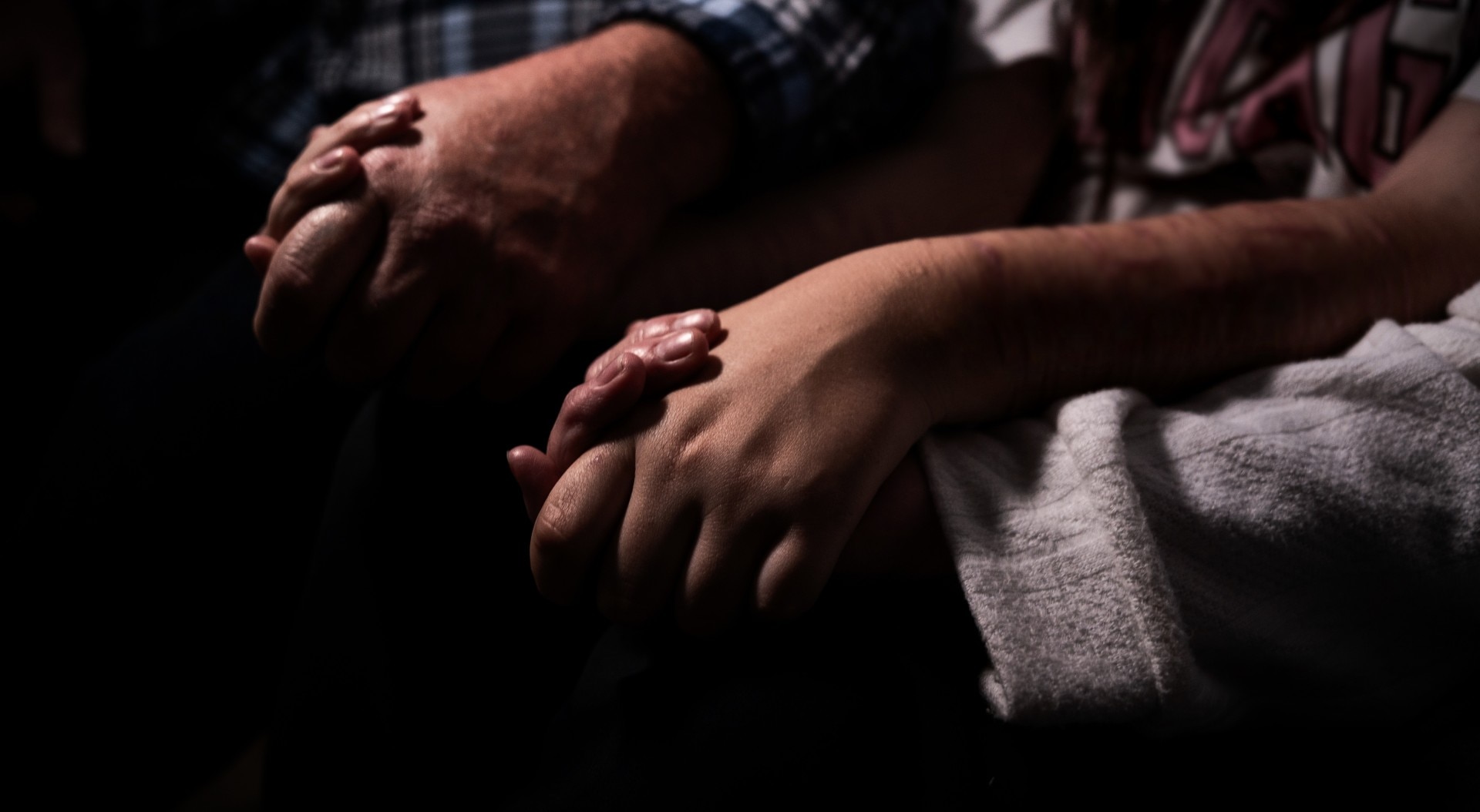 A man and his daughter hold hands on a couch.