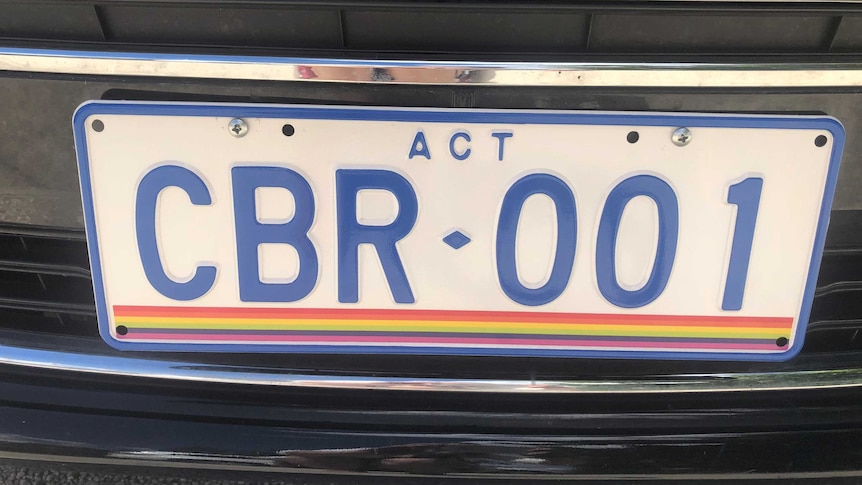 A license plate with rainbow stripes at the bottom.