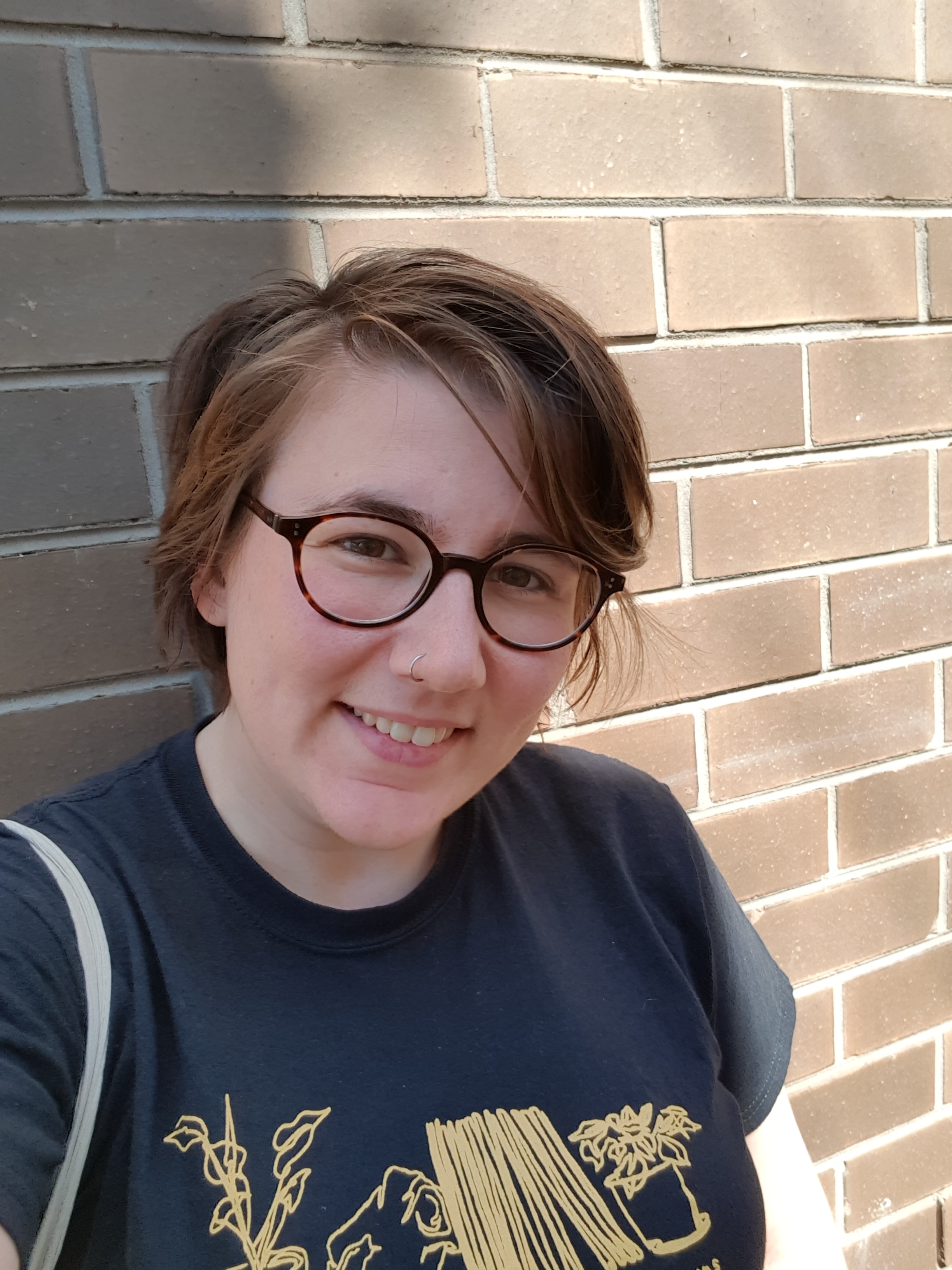 Jacinta Bowler smiles while standing against a wall.
