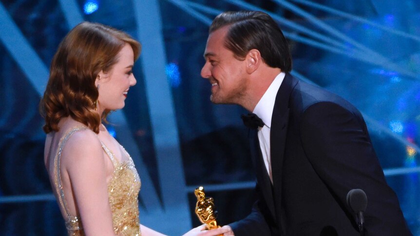 Leonardo DiCaprio, right, presents Emma Stone with the award for best actress.