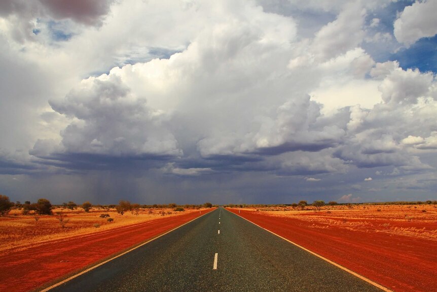 A stormy sky over a highway in the red dirt of central Australia.