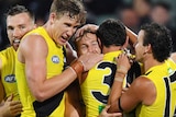 A number of Richmond players congregate around Kane Lambert and give him a hug