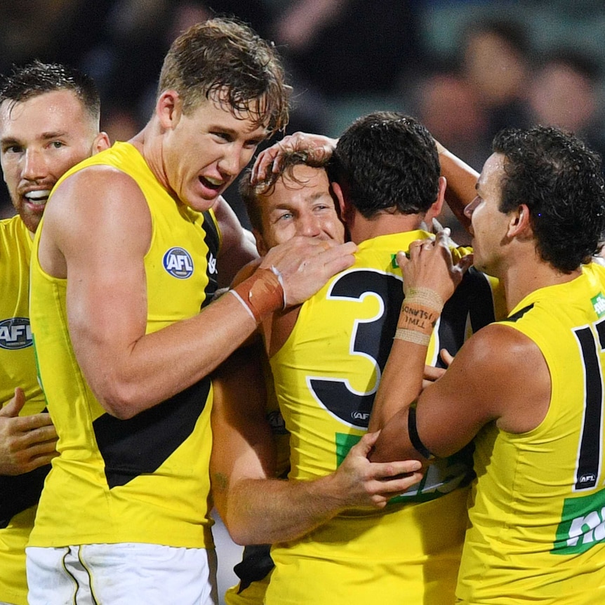A number of Richmond players congregate around Kane Lambert and give him a hug
