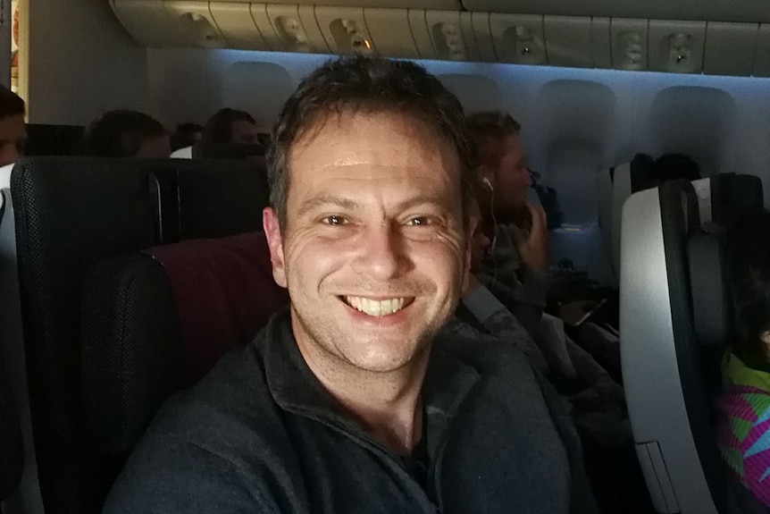 Former Waverley councillor and lawyer Sam Einfeld smiling in the darkened cabin of a plane