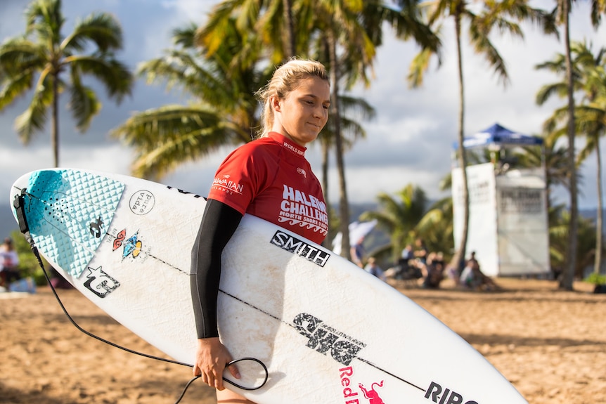 An Australian female surfer prepares to enter the water during a competition in Hawaii.