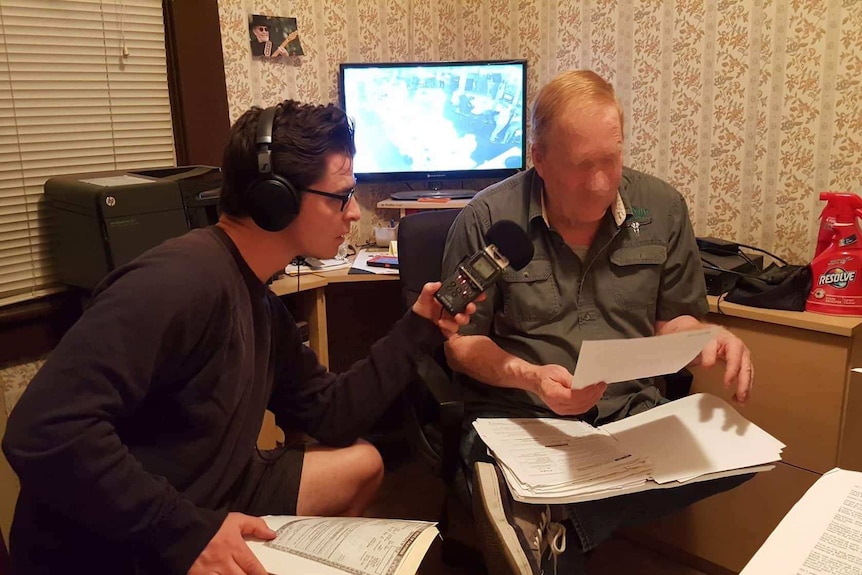 Two men looking at documents and recording an interview.