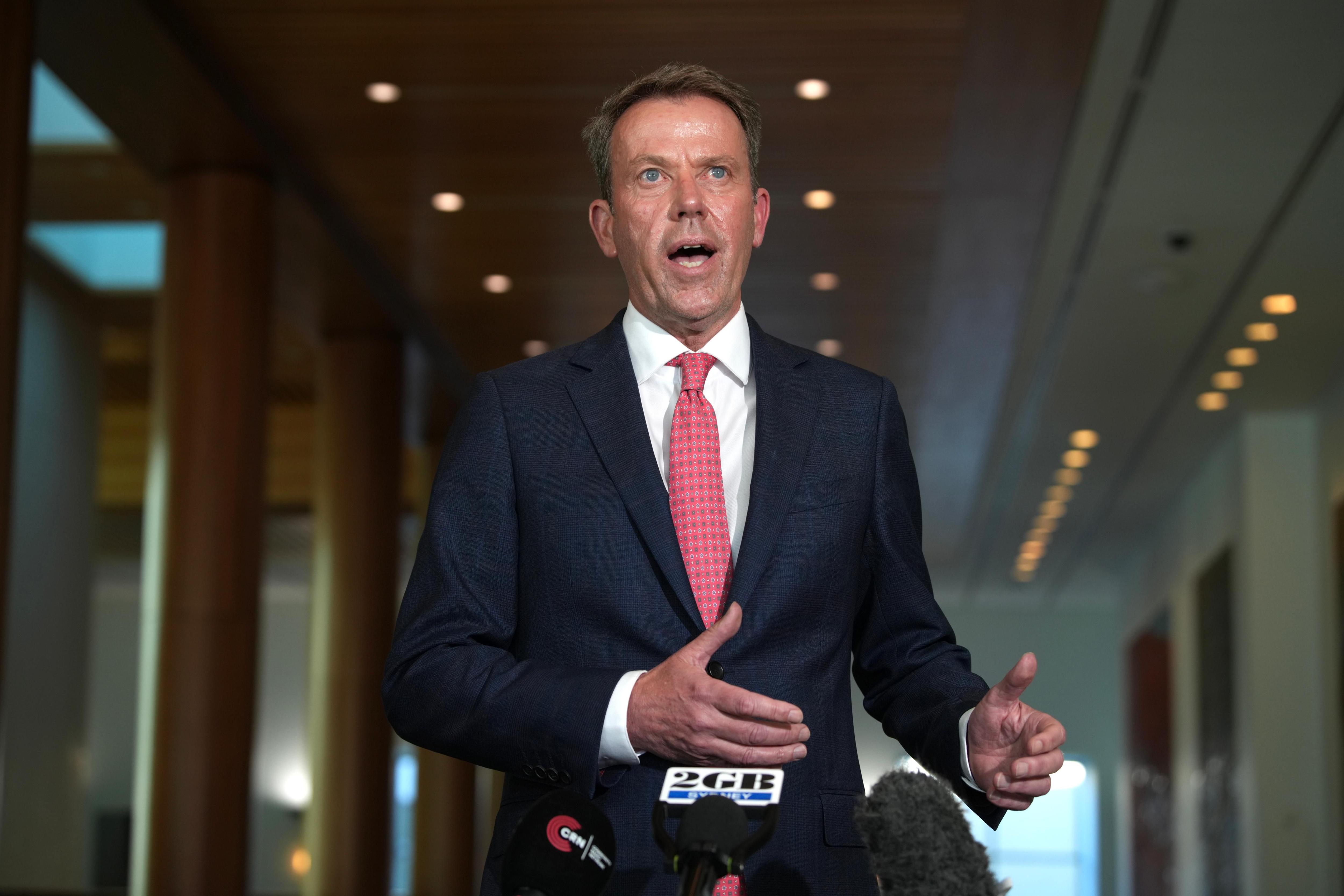 um homem vestindo terno e gravata rosa falando dentro do parlamento