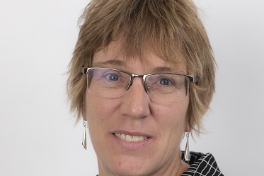 Middle aged woman with glasses and a dark-coloured shirt