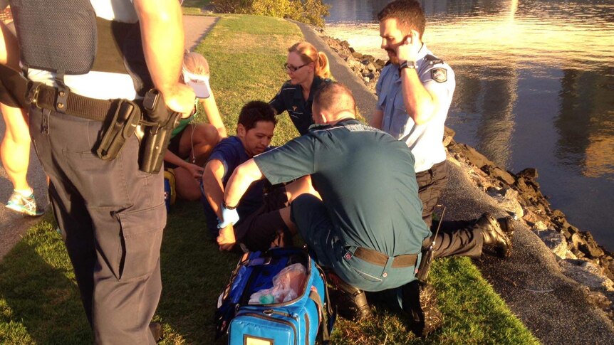 Police and ambulance officers tend to a man who fell into the Brisbane River at South Bank.
