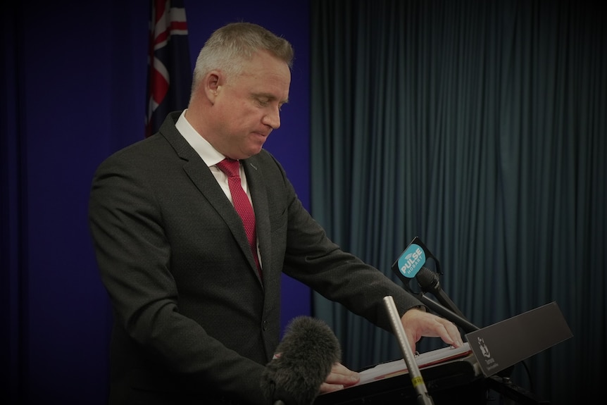 Jeremy Rockliff looking down while speaking at a lectern.