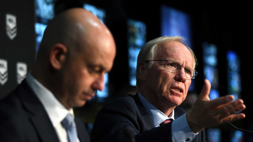 Todd Greenberg looks down in the foreground while Peter Beattie points towards the room.