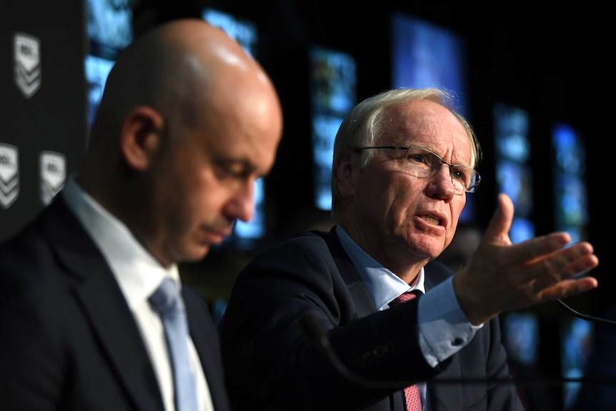 Todd Greenberg looks down in the foreground while Peter Beattie points towards the room.