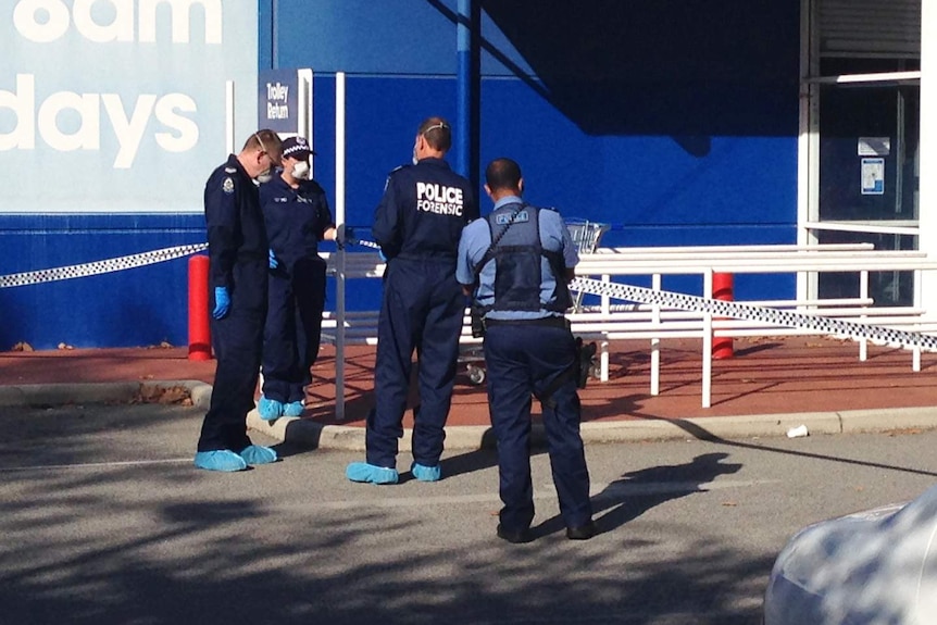 Three police forensics officers and another officer stand outside an Officeworks shop with police tape guarding the entrance.