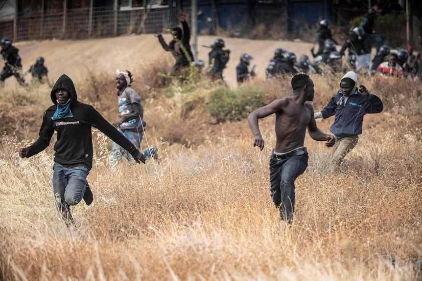 Migrants run on Spanish soil after crossing a border fence