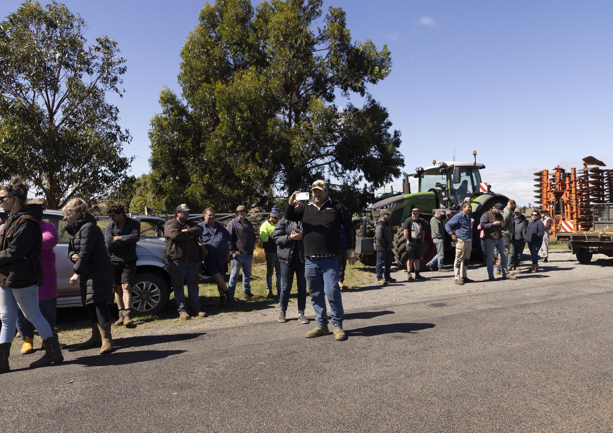 People and farm equipment form a blockade outside a rural property.