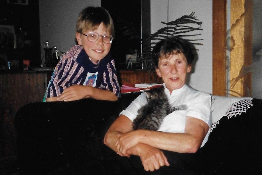 A black and white photo of a woman with her grandson, who is wearing glasses.